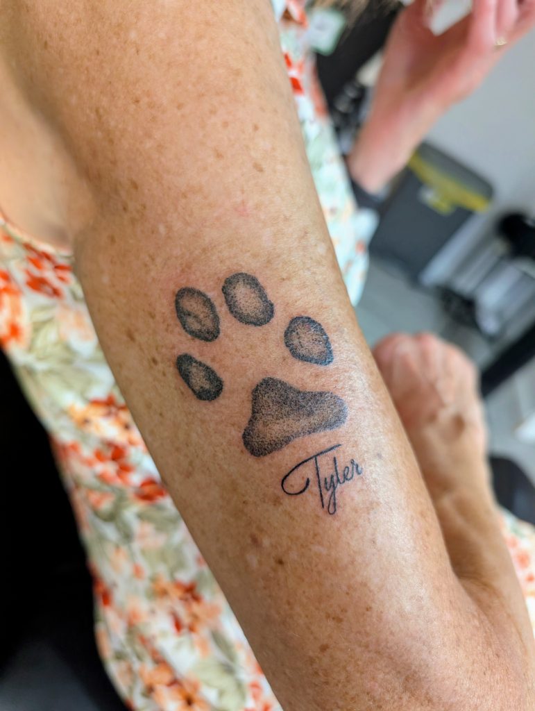 181b3e3b-7e2b-4b4e-9169-fa9052f7ab8c~1 Script paw print arm tattoo by Leanne at Kimmer Ink Tattoo Studio in Eastleigh, Hampshire.