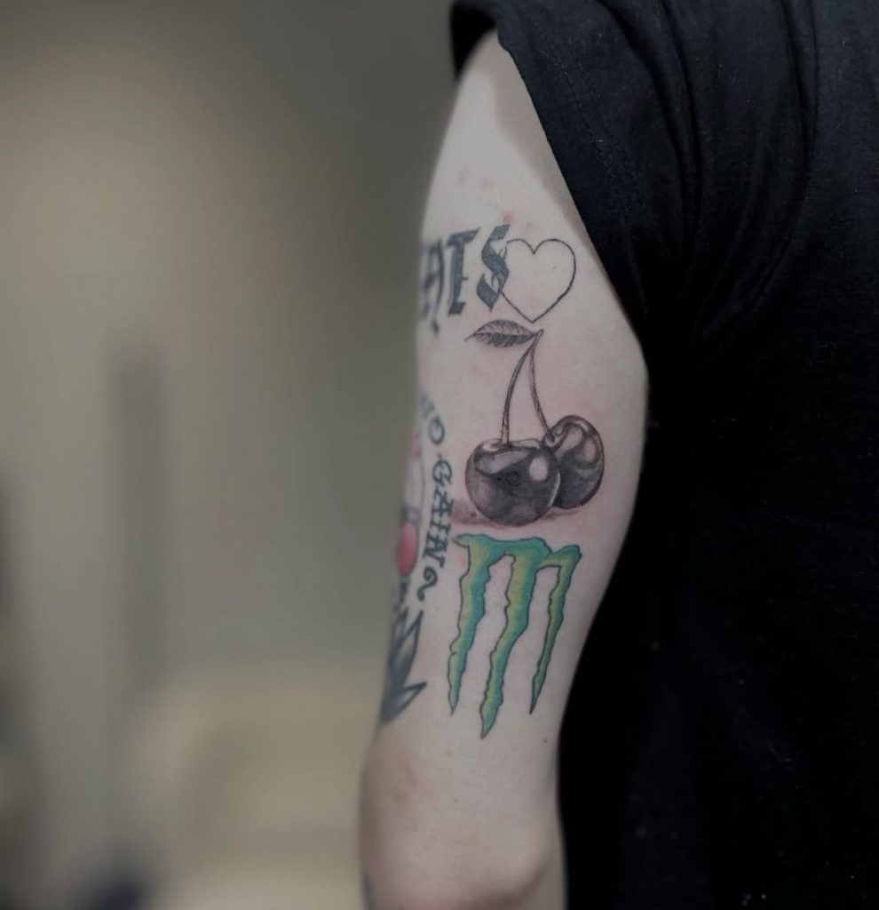 71a960fb-5c4d-4a74-bd1f-5d78071ecf8c American traditional colour tattoo of a Monster Energy logo with cherries by Loren at Kimmer Ink Tattoo Studio in Eastleigh, Hampshire.